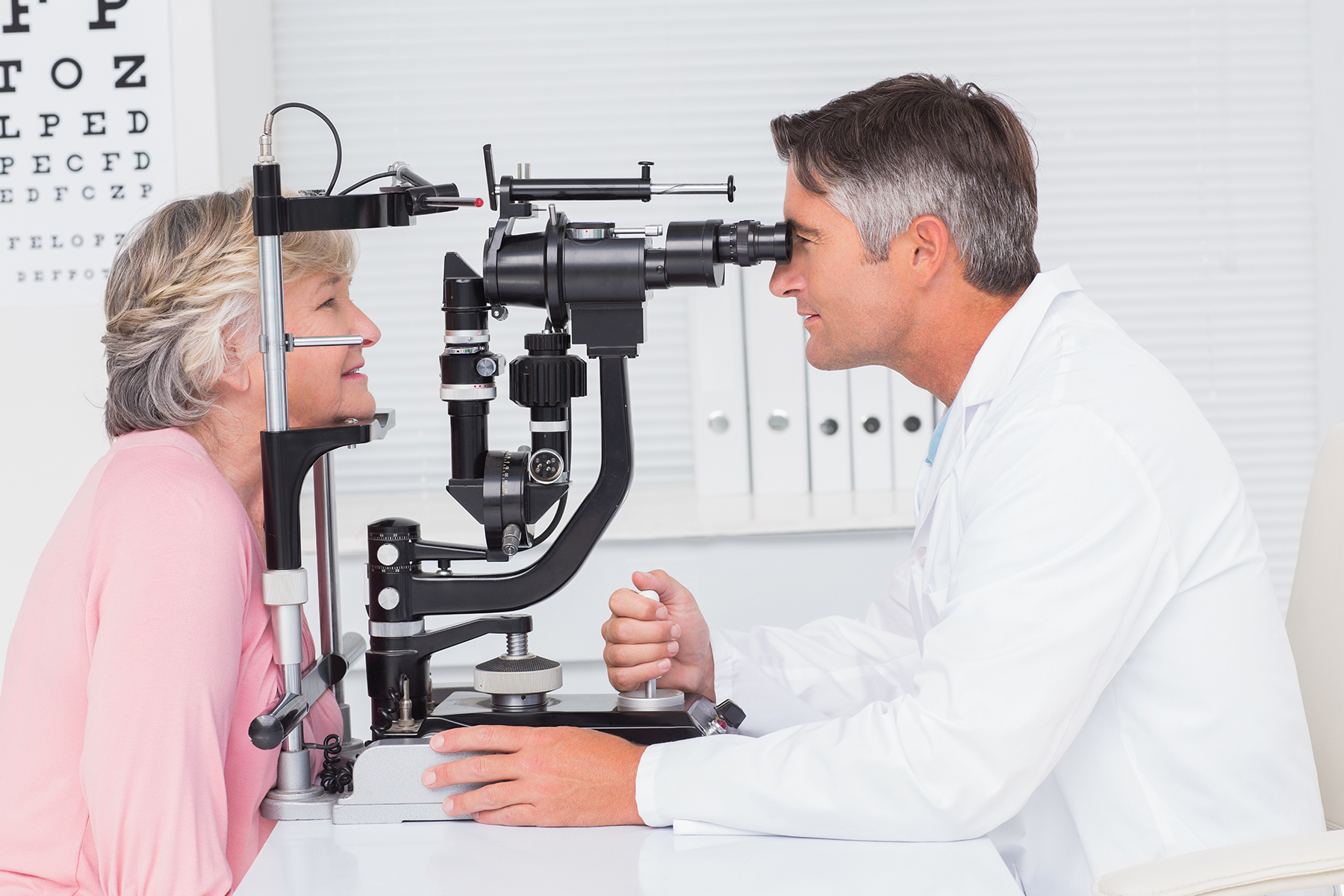 eye care professional performing an eye exam to a senior