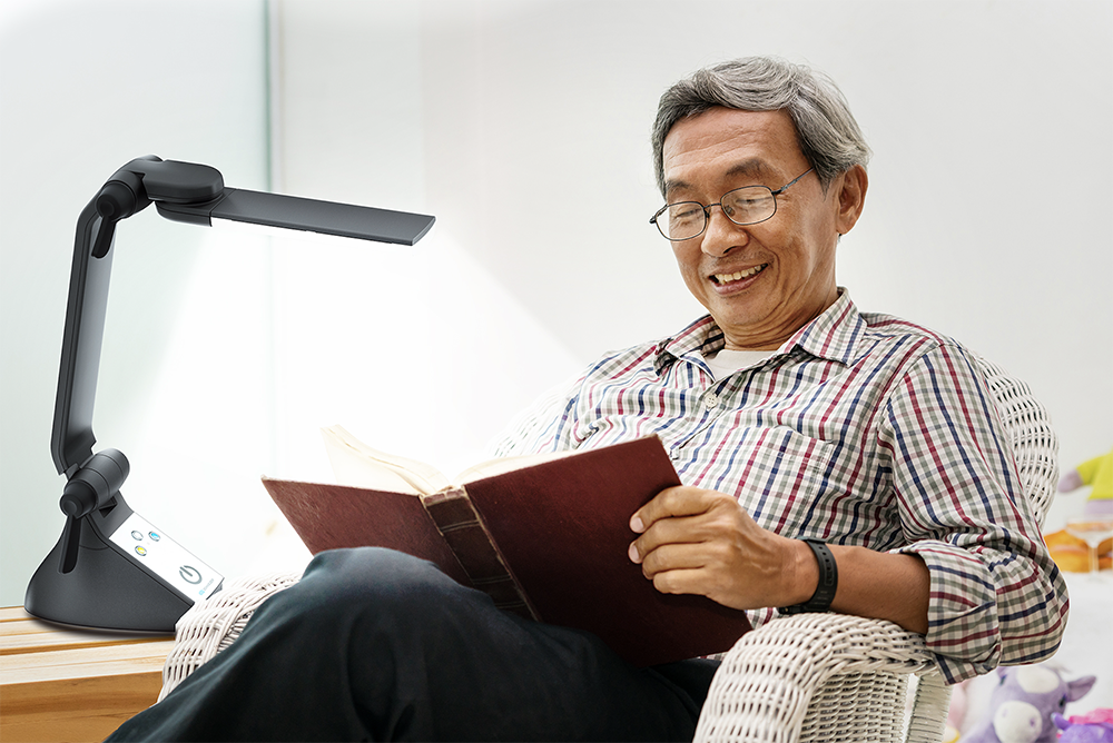 Man reading a book using a desk lamp