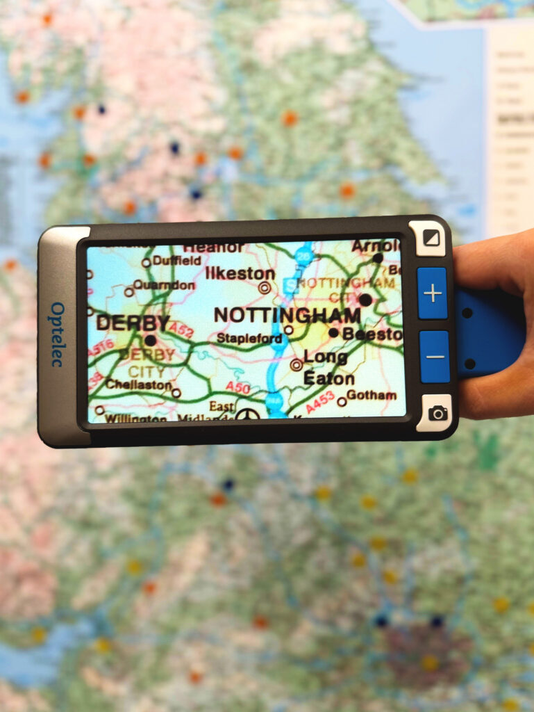 Someone holding the Compact Go by its handle, that is pointed at a UK map, on the screen the areas of Nottingham and Derby are magnified
